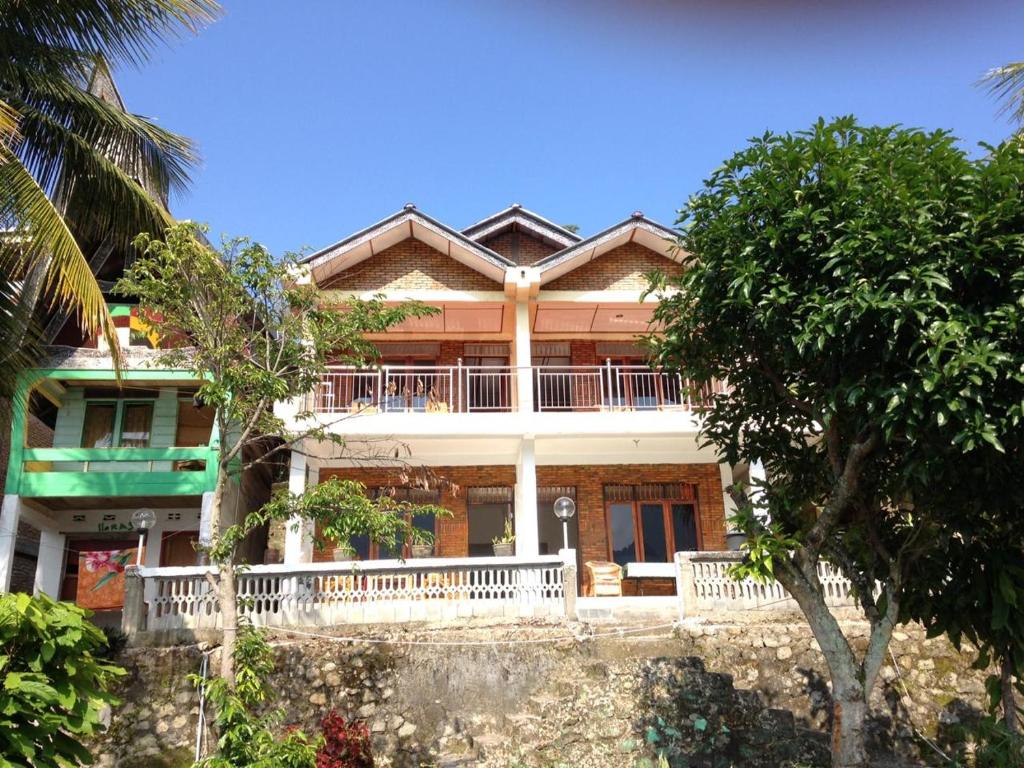 a large house with a balcony and trees at Aman's Guesthouse in Tuktuk Siadong