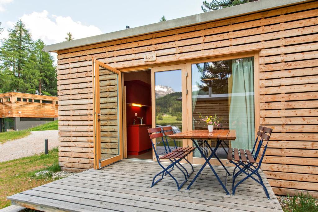 eine kleine Hütte mit einem Tisch und Stühlen auf einer Terrasse in der Unterkunft Camping Gravatscha in Samedan