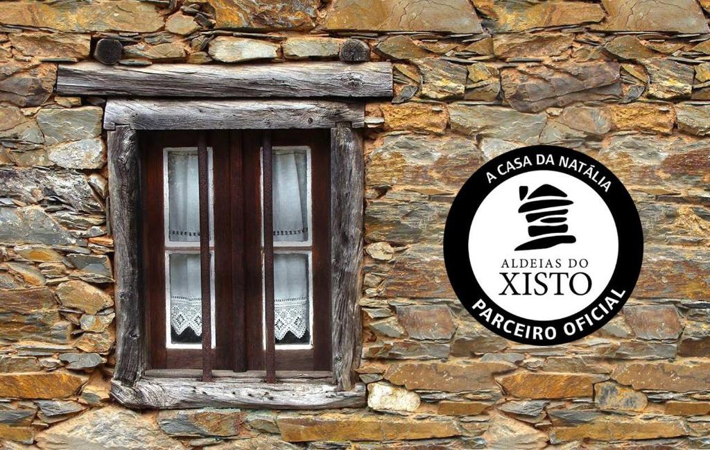 una señal en el lateral de un edificio de piedra con una ventana en A Casa da Natália, en Alvares