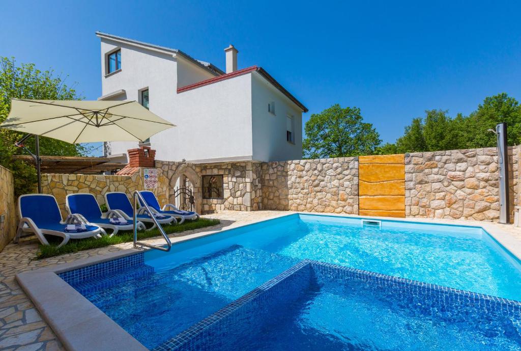 uma piscina com cadeiras e um guarda-sol ao lado de uma casa em Apartment LINDA em Grižane