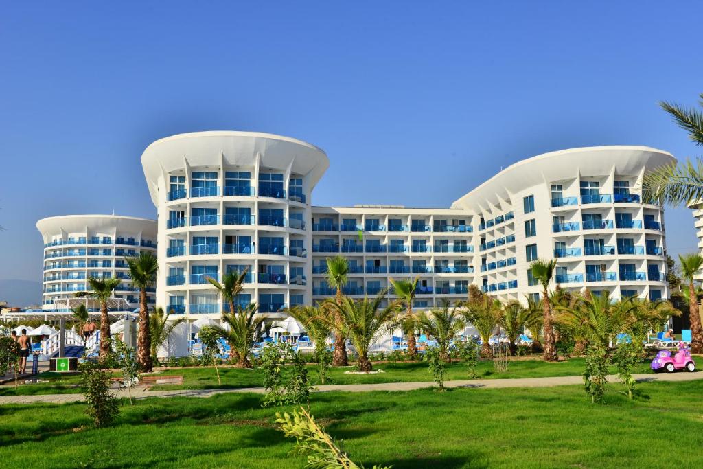 a large white building with palm trees in front of it at Sultan of Dreams Hotel & Spa in Kızılot