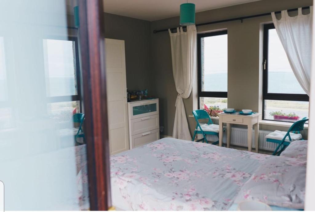 a bedroom with a bed and a desk and two windows at Our View in Doolin