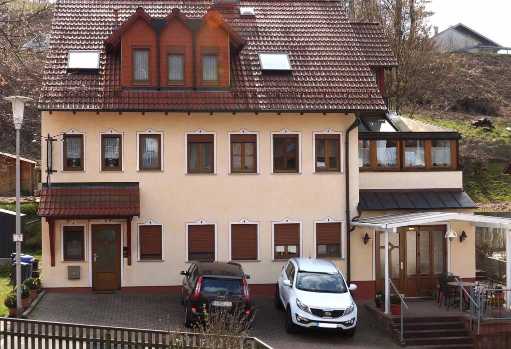 una casa con dos coches estacionados frente a ella en Ferienwohnung im Hainertal, en Heigenbrücken