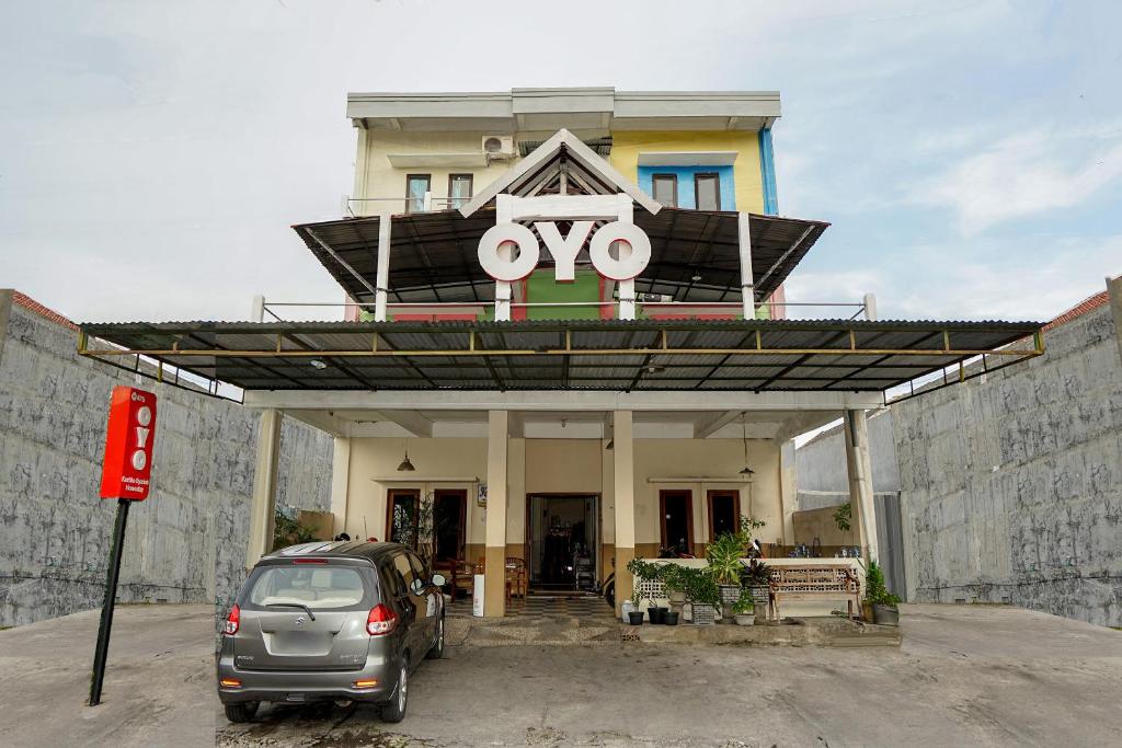 een auto geparkeerd voor een gebouw met een ovy bord bij Kartika Syariah Homestay by Stayku in Surabaya