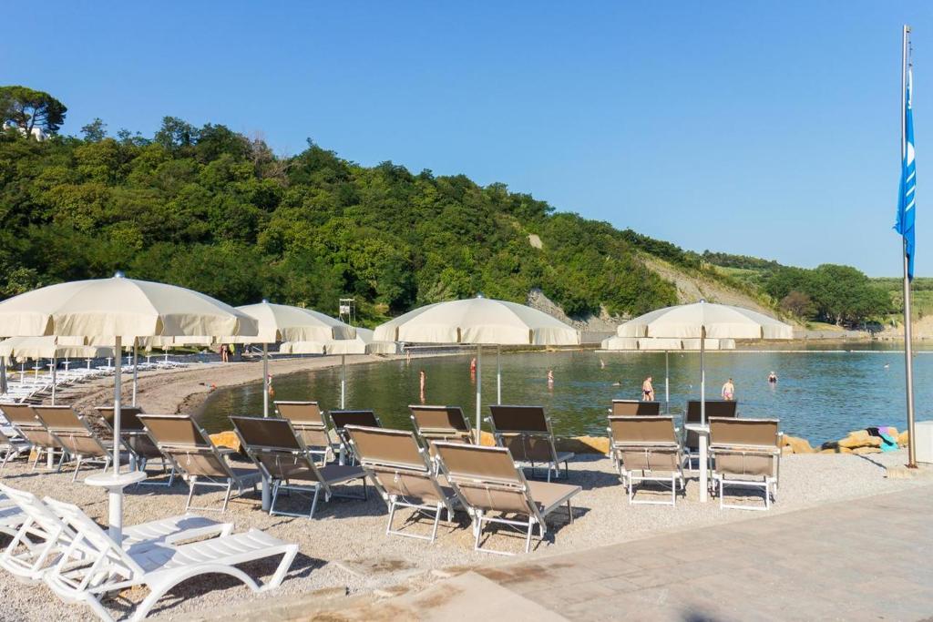 a group of chairs and umbrellas on a beach at Apartments ROKO in Izola