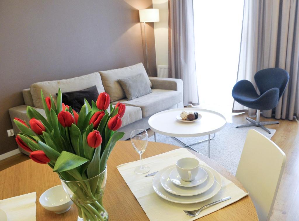 a living room with a vase of red tulips on a table at IRS ROYAL APARTMENTS Apartamenty IRS Fregata in Gdańsk