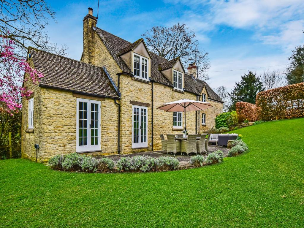 an old stone house with an umbrella in the yard at Westerleigh Cottage in Cheltenham