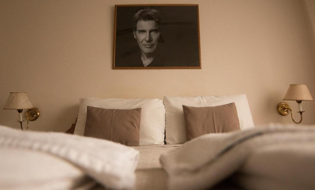 un dormitorio con una cama con un retrato de hombre en el Hotel de Cine Las Golondrinas de Villa Gesell