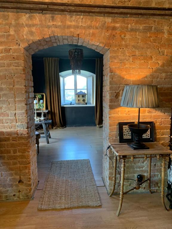 a room with a brick wall and a table with a lamp at The Piano Shop in Gränna