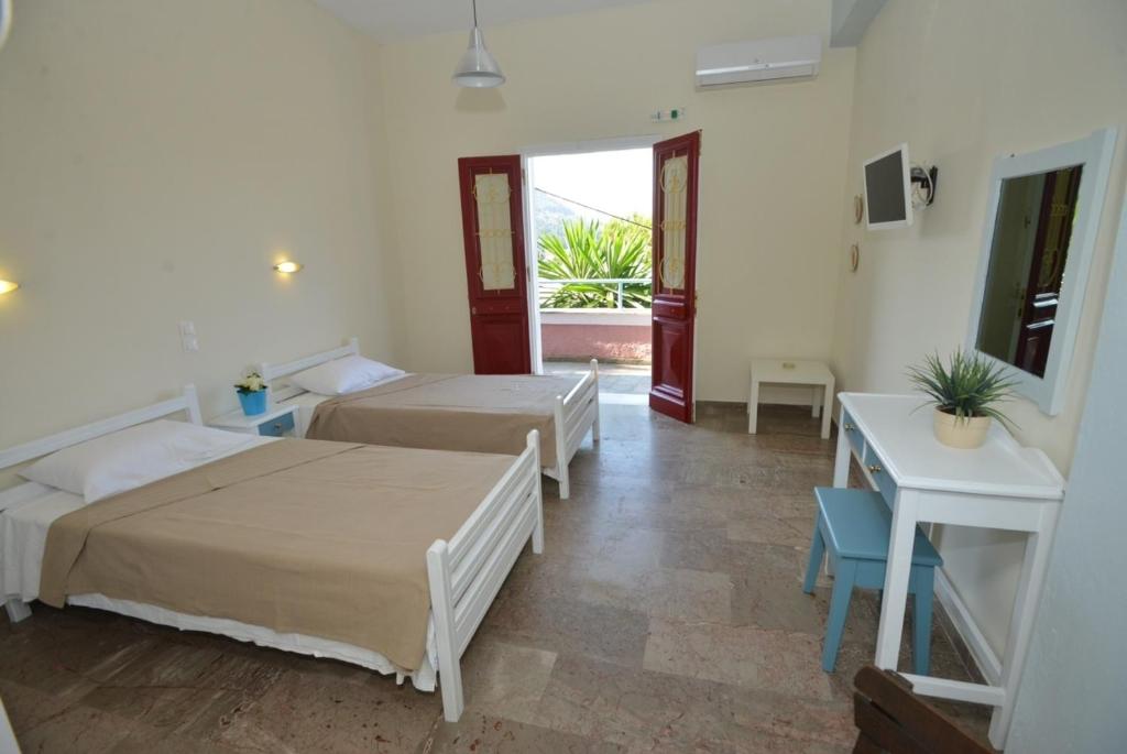 1 dormitorio con 2 camas, mesa y ventana en Kontos Mansion, en Benitses