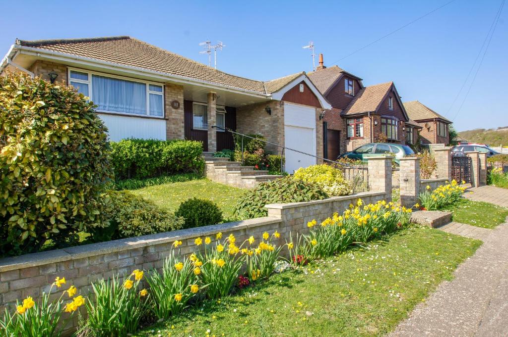 a house with a garden with flowers in the yard at Dean Court Bungalow - Parking - by Brighton Holiday Lets in Rottingdean
