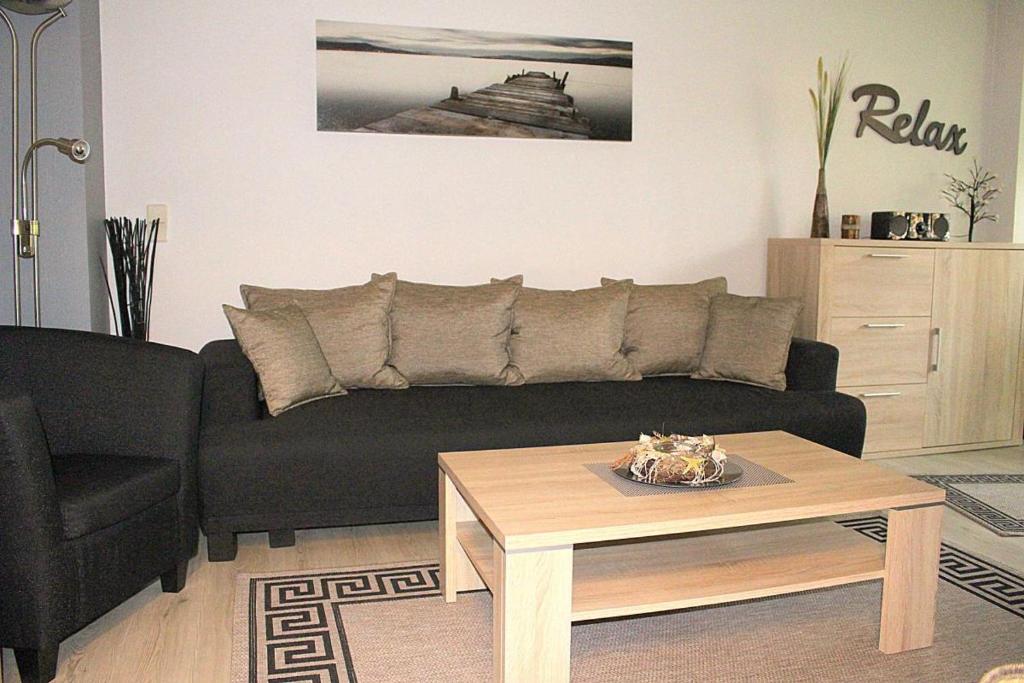 a living room with a black couch and a coffee table at Apartmentvermittlung Mehr als Meer - Objekt 78 in Niendorf
