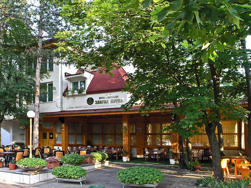 un bâtiment avec des tables et des chaises devant lui dans l'établissement Хотел ЗЛАТНА КОТВА, à Kazanlak