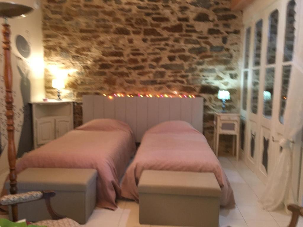 a bedroom with two beds and a brick wall at Le roc de l&#39;aigle in Cabrespine