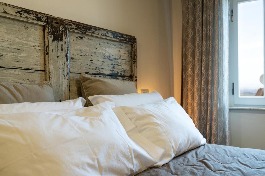 a bed with white sheets and a wooden headboard at Caratello smart studio Apt in Montepulciano