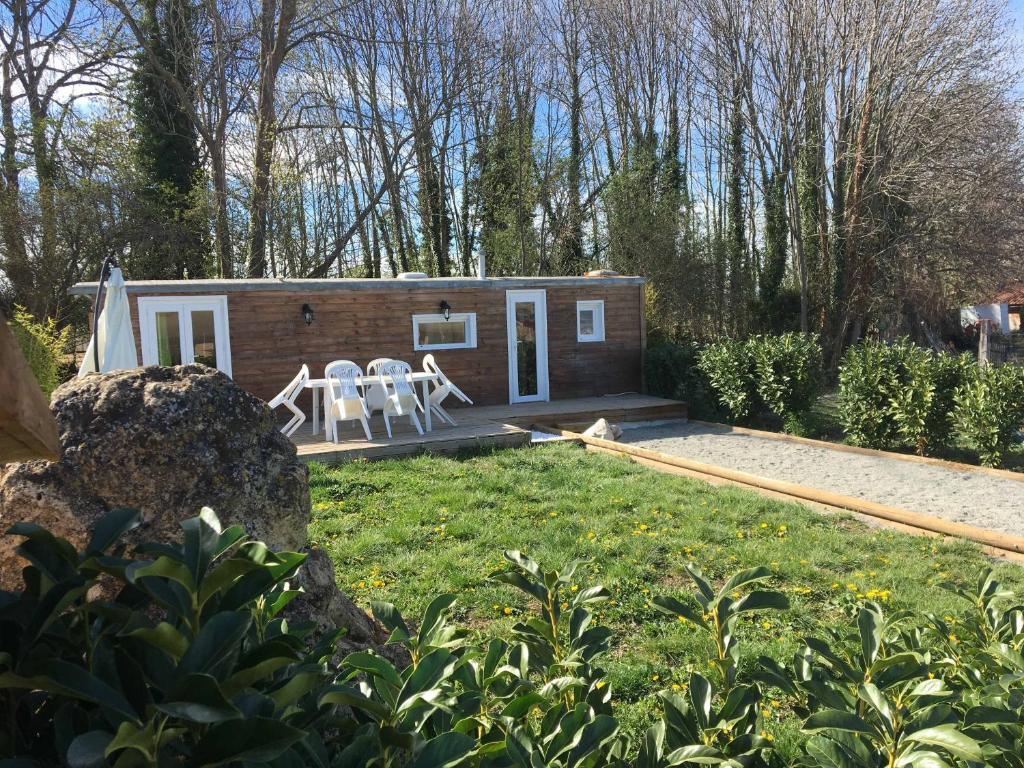 une petite maison dans un jardin avec deux chaises blanches dans l'établissement Chevrerie des Oliviers, à Saint-Georges-sur-Allier