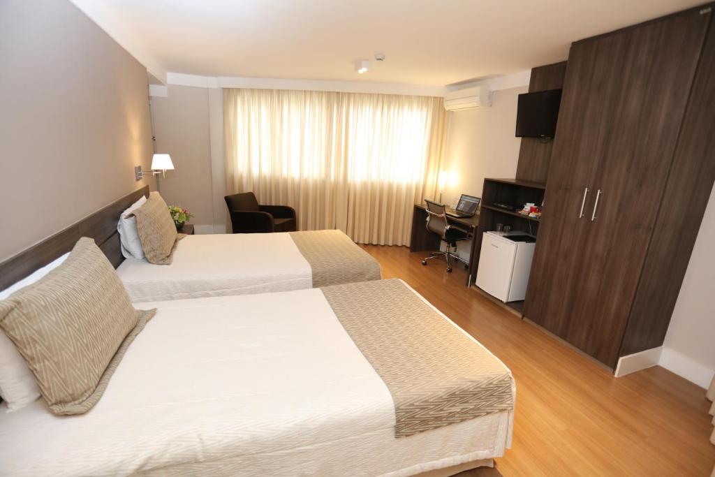 a hotel room with two beds and a desk at Hotel Trianon Paulista in Sao Paulo