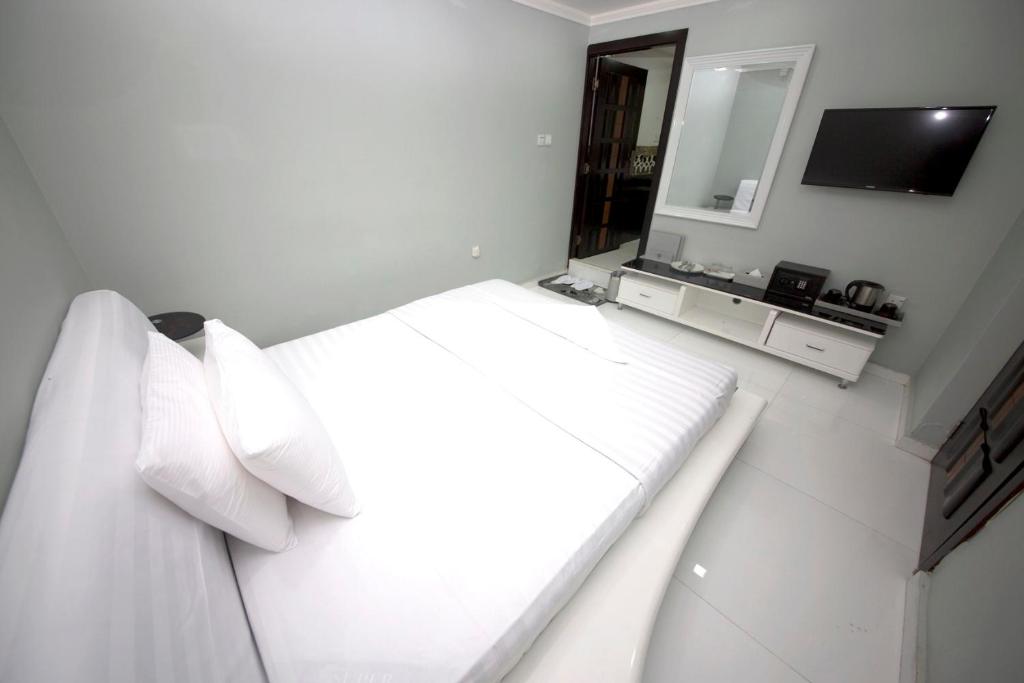 a white bedroom with a bed with pillows and a mirror at White Fort Hotel in Dubai
