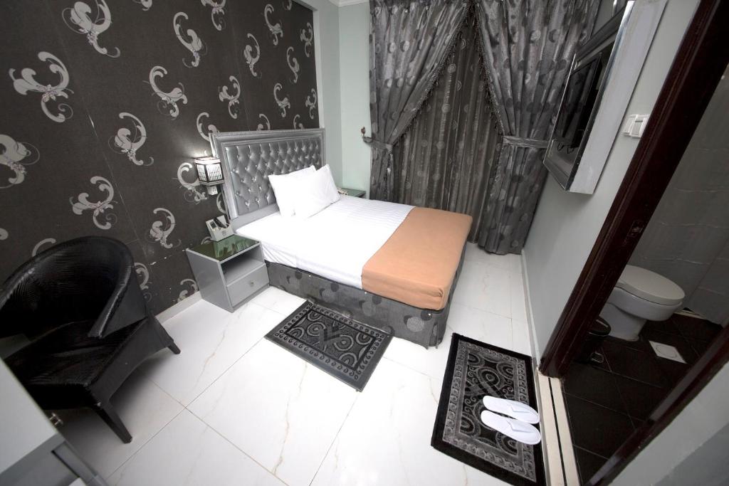 a small bedroom with a bed and a chair at White Fort Hotel in Dubai