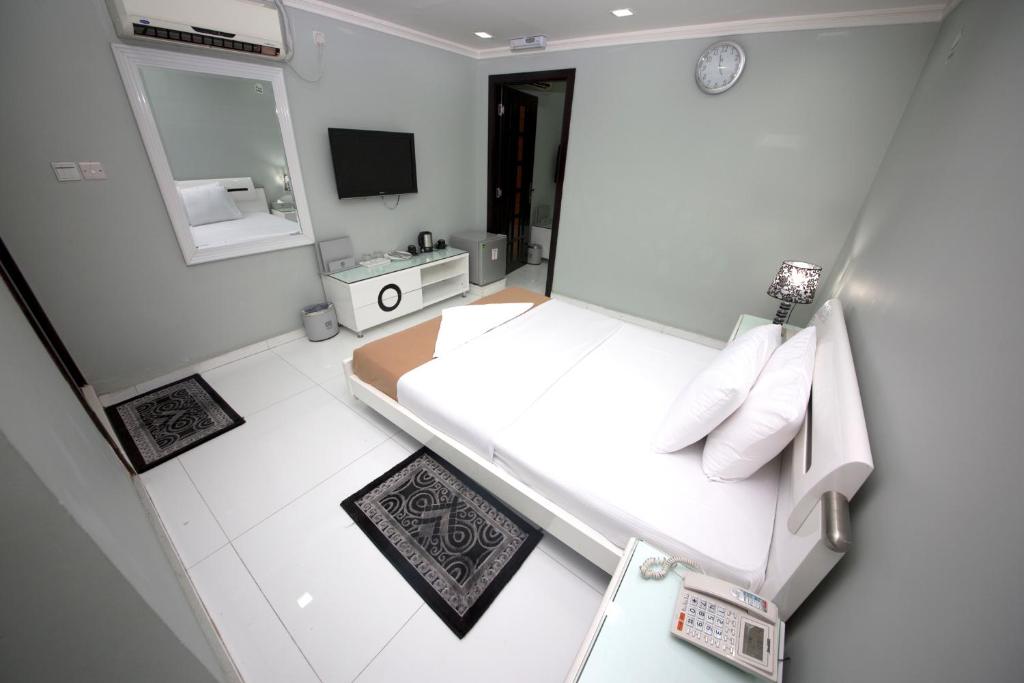 a small white bedroom with a bed and a mirror at White Fort Hotel in Dubai
