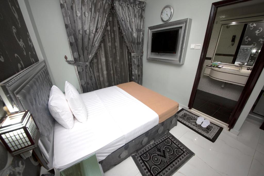 a bedroom with a bed and a bathroom with a sink at White Fort Hotel in Dubai