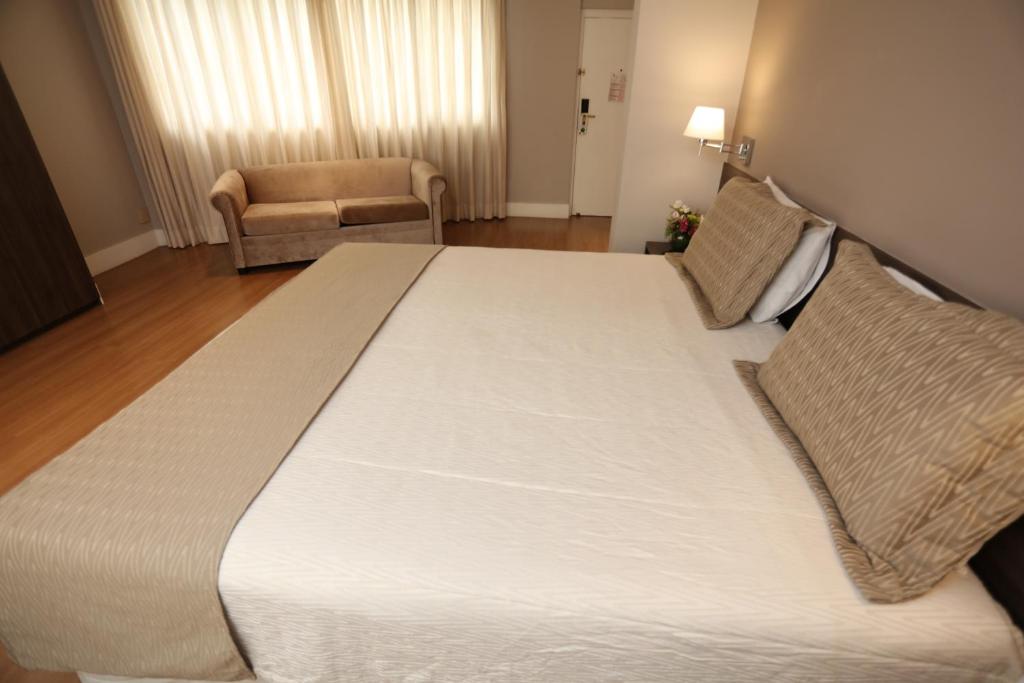 a large white bed in a room with a chair at Hotel Trianon Paulista in Sao Paulo