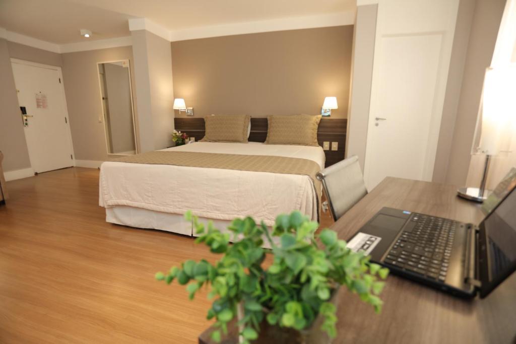 a bedroom with a bed and a laptop on a table at Hotel Trianon Paulista in Sao Paulo
