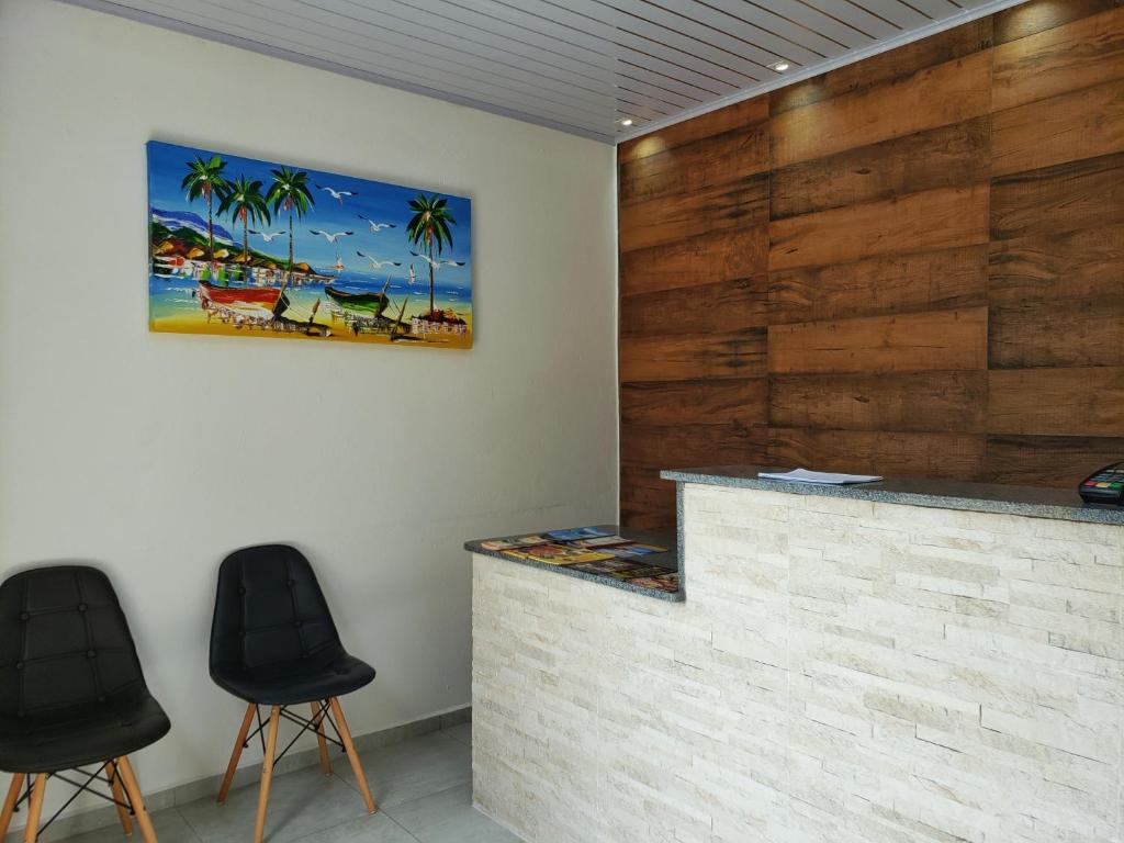 un bar con 2 taburetes negros en una habitación con paredes de madera en Pousada Praia Vermelha, en Penha