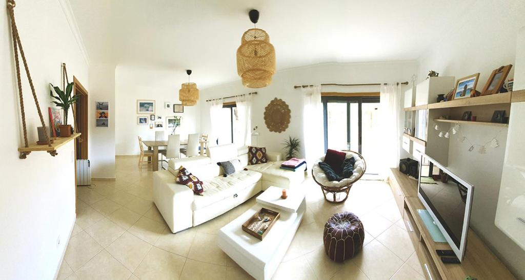 a living room with a white couch and a tv at Casa Mawi in Sagres