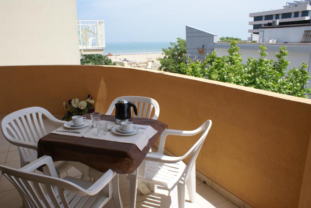 una mesa y sillas en un balcón con vistas a la playa en Residence Domus, en Rímini
