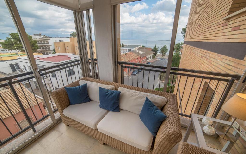 un sofá de mimbre en un balcón con almohadas azules en Apartamento con vistas al mar, en Santiago de la Ribera