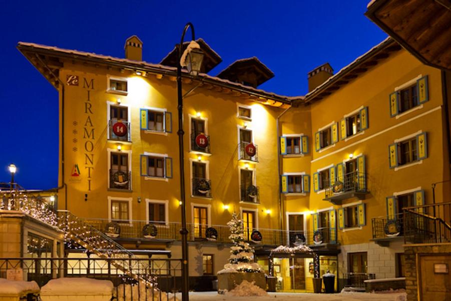 - un grand bâtiment jaune avec des lumières de Noël dans l'établissement Le Miramonti Hotel Restaurant & Wellness, à La Thuile