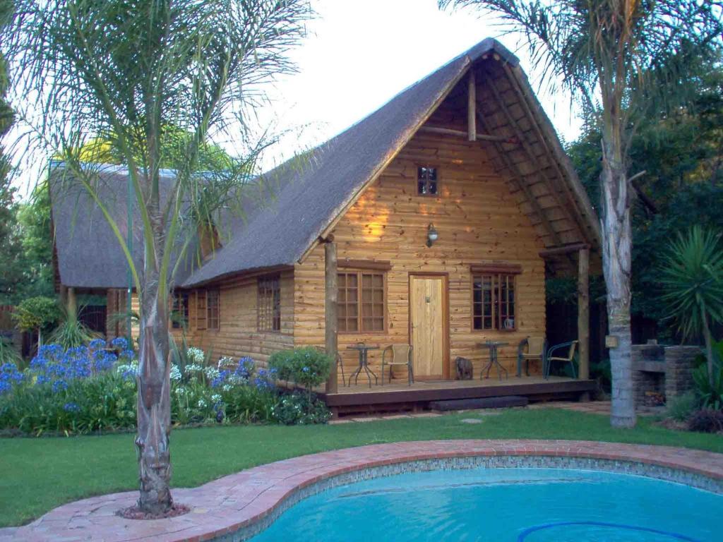 a log cabin with a pool in front of it at Ciara Guesthouse in Pretoria