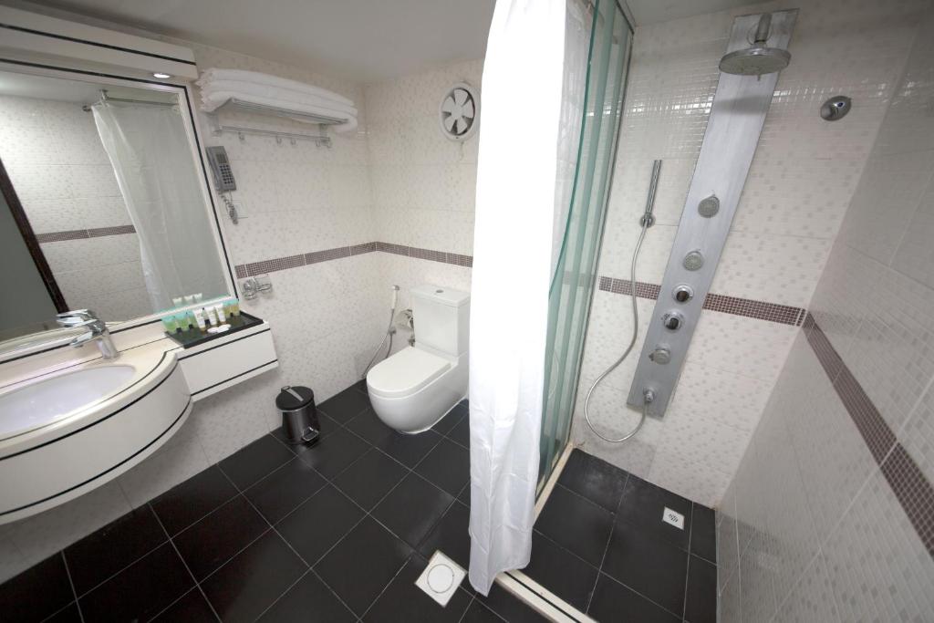 a bathroom with a toilet and a sink and a shower at White Fort Hotel in Dubai