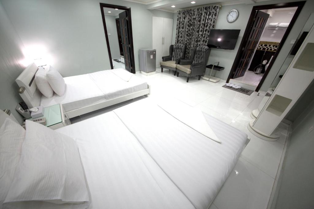a white living room with a couch and a television at White Fort Hotel in Dubai