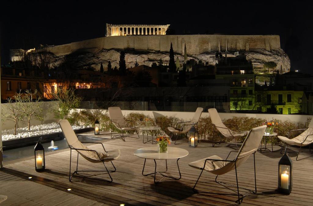 a patio area with chairs, tables and umbrellas at Herodion Hotel in Athens