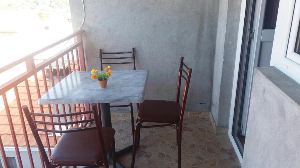 a table and chairs with a vase of flowers on a balcony at Guesthouse Stankovic in Sutomore