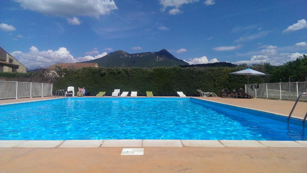une grande piscine bleue avec une montagne en arrière-plan dans l'établissement Golf Resort de Digne-les-bains by Adonis, à Digne-Les-Bains
