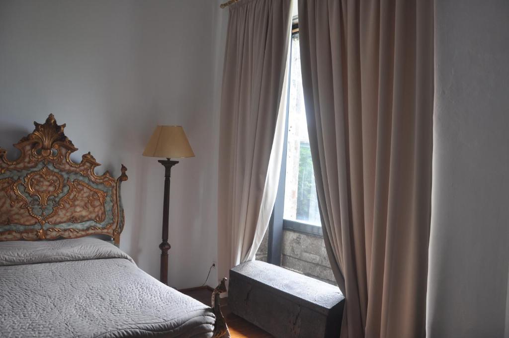 a bedroom with a bed and a window with curtains at Convento de São Francisco in Vila Franca do Campo