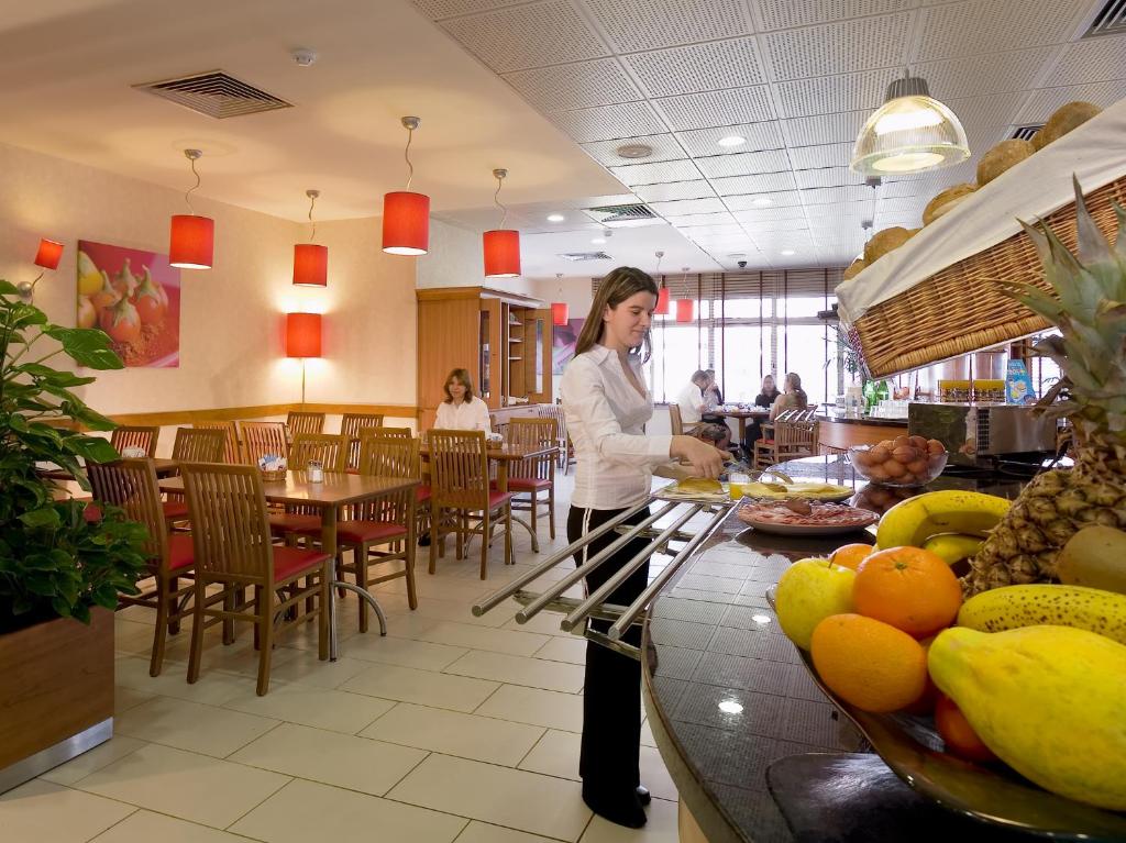 A bright breakfast room with a buffet counter, fresh fruit and staff preparing food.