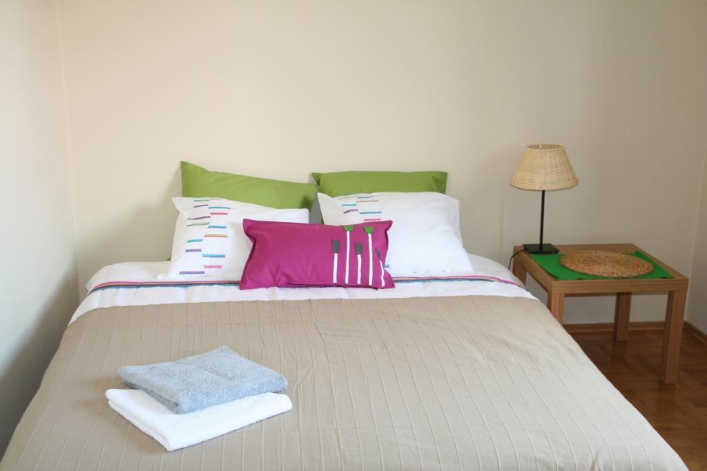 łóżko z białymi i różowymi poduszkami i stołem w obiekcie Villa Zakoniczynka w Gdańsku