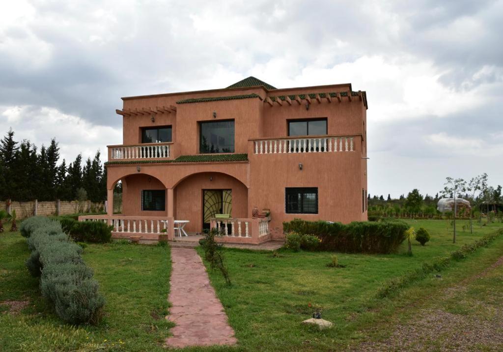 a large brick house with a bench in front of it at Villa Moderne dans la Ferme "Belkheir" avec Piscine, Chevaux et Aire de Jeux pour Enfants in Berrechid