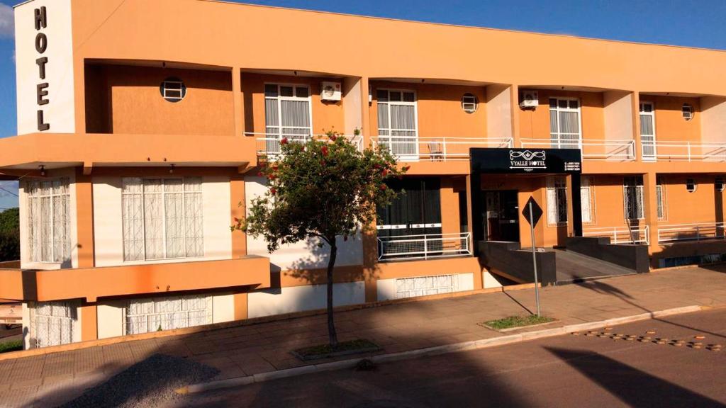 Vyalle Hotel في ماشادينهو: مبنى برتقالي امامه شجرة