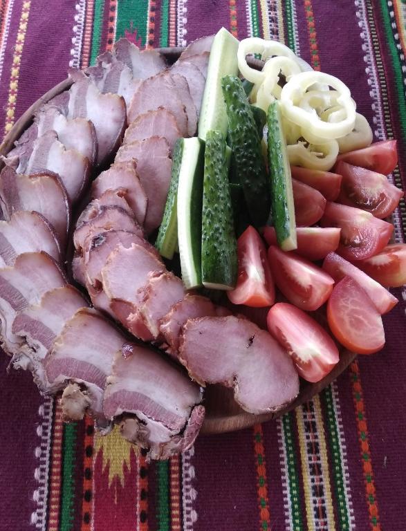 a plate of meat and vegetables on a table at Садиба Там де гори in Krivorovnya