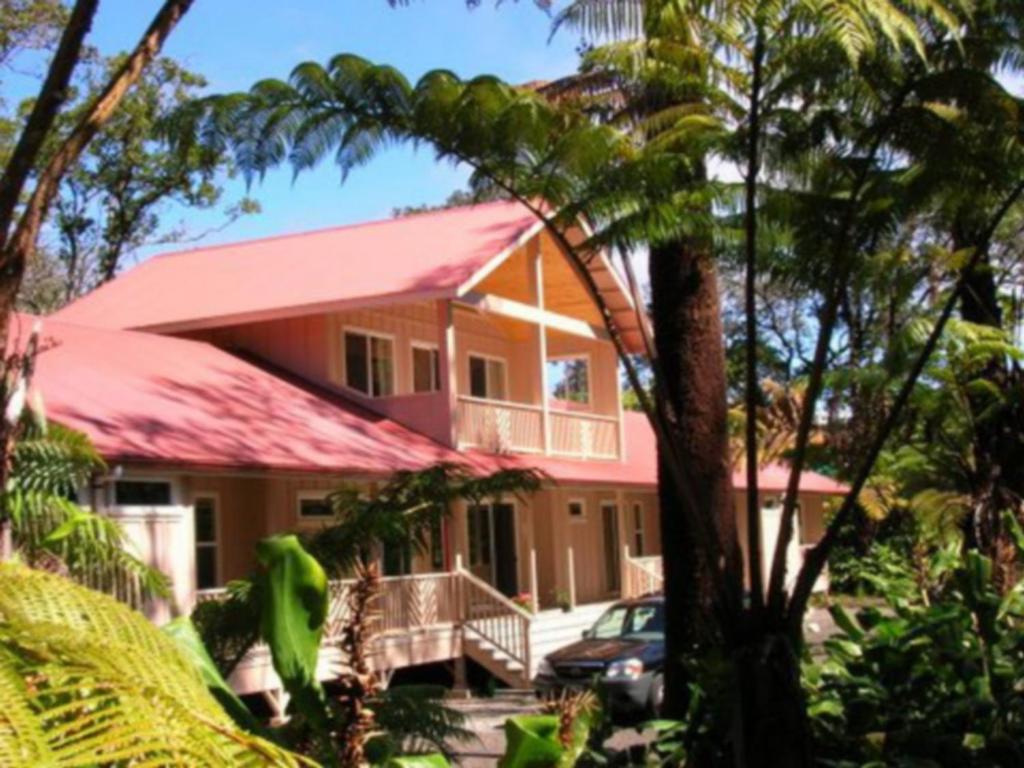 una casa con techo rojo y un coche aparcado delante en Volcano Forest Inn en Volcano