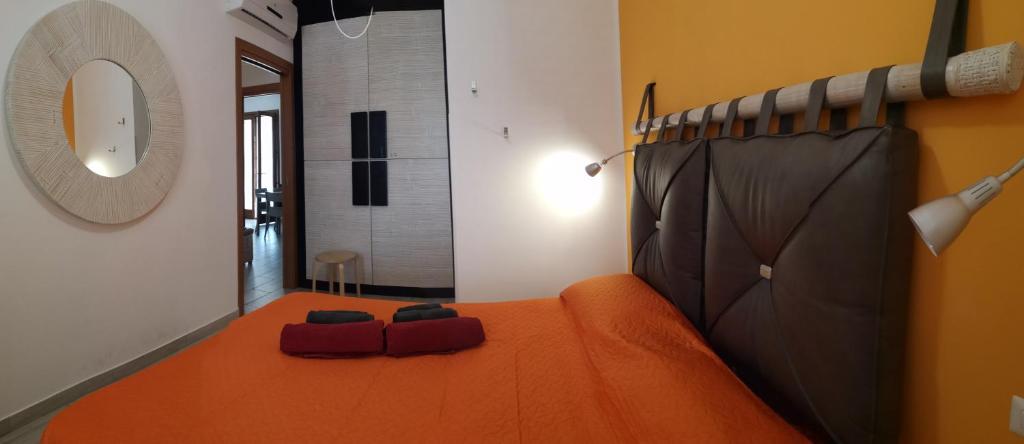 a bedroom with an orange bed and a mirror at Casa Frida in San Vito lo Capo