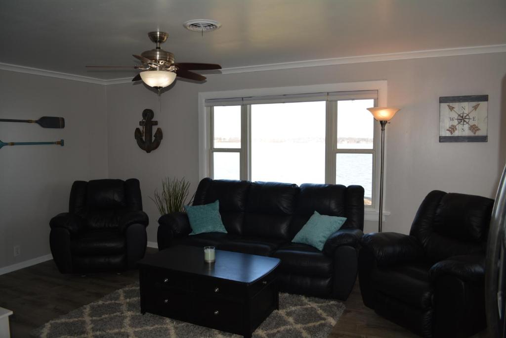a living room with black leather furniture and a ceiling fan at Stafford Lake House in McHenry