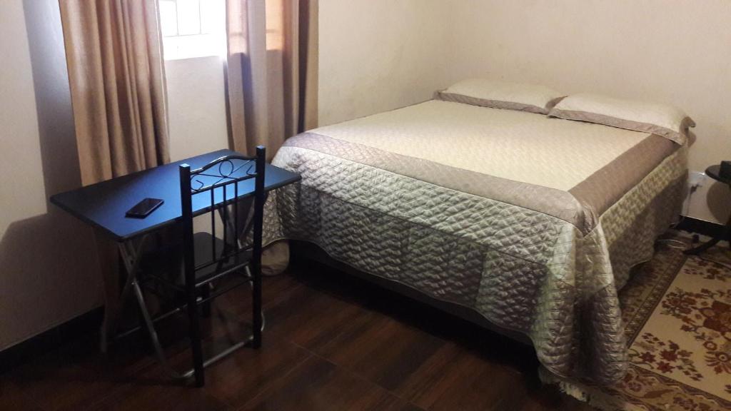 a small bedroom with a bed and a side table at Furnished self catering cottage in Lusaka
