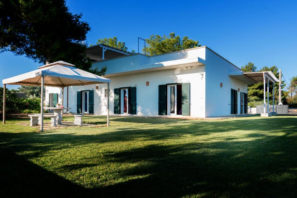 a white house with an umbrella in a yard at Aura Solis B&B in Leuca