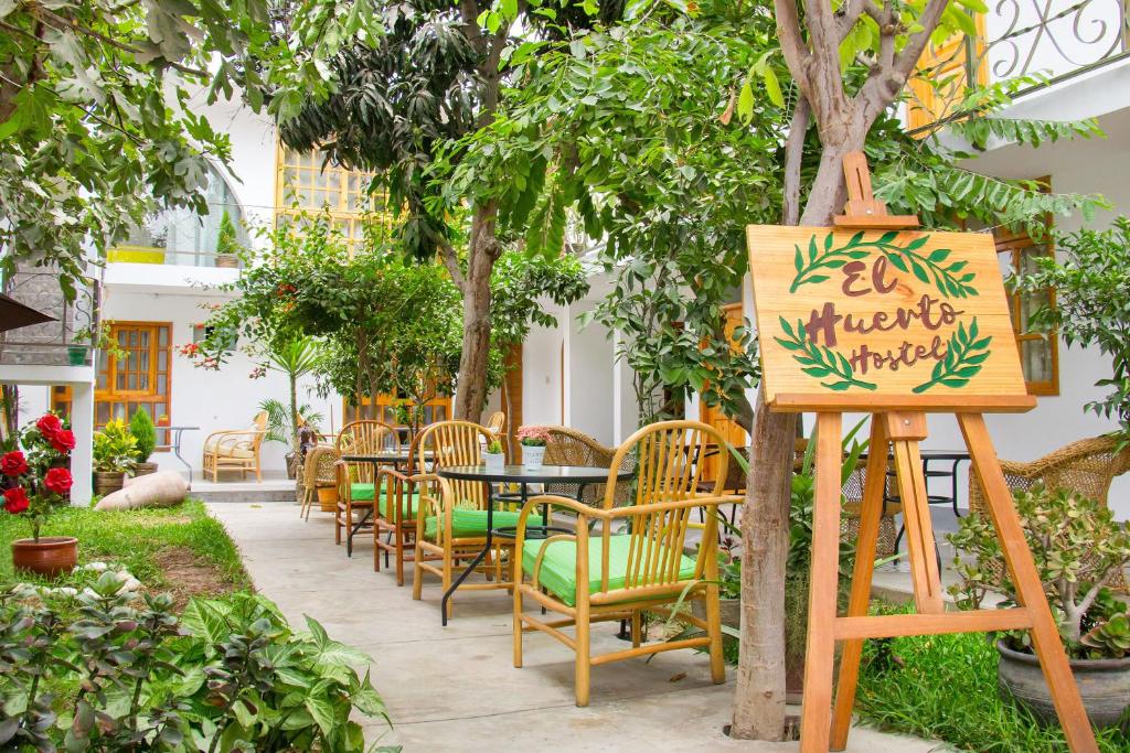 a garden with tables and chairs and a sign at El Huerto Hostel in Ica